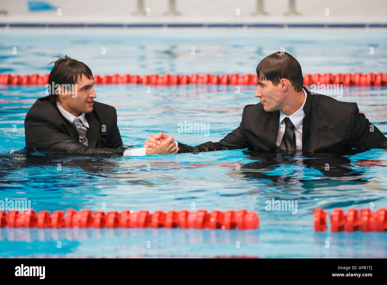 Gli imprenditori ad umido stringono le mani in piscina Foto Stock