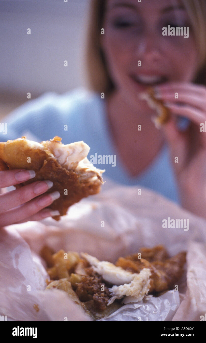 La donna a mangiare pesce e patatine da carta Foto Stock