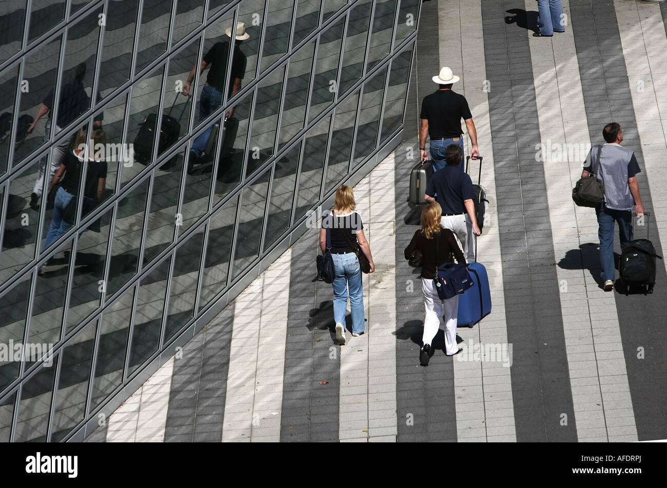Illustrazione viaggi: viaggiatori con bagaglio riflettendo in una facciata di vetro a all'aeroporto di Monaco di Baviera, Reisende mit Gepaeck Foto Stock
