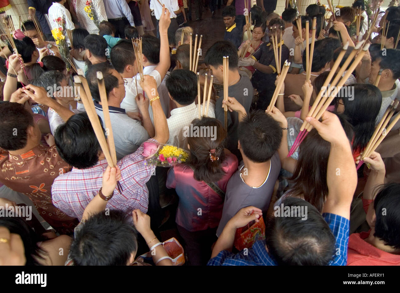 Una folla di persone che si tengono per bruciare i bastoncini di incenso rendendo il loro modo in un tempio cinese per il festival di primavera di celebrazioni Foto Stock