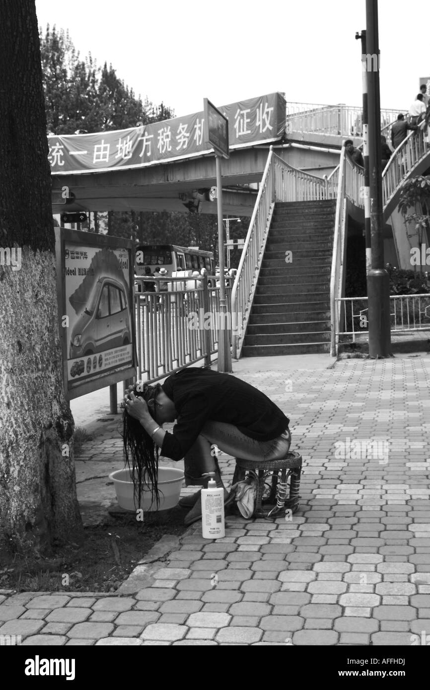 Una donna lava i capelli sul lato della strada in Kunming, nella provincia dello Yunnan in Cina. Foto Stock