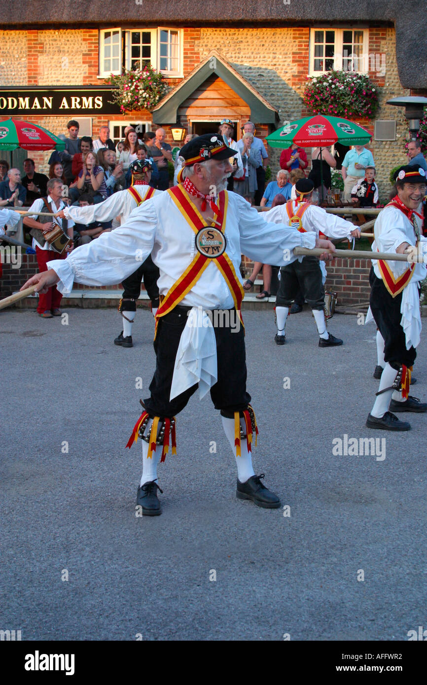 Morris ballerini eseguono balli tradizionali al di fuori di un pub Inglese di sera Foto Stock