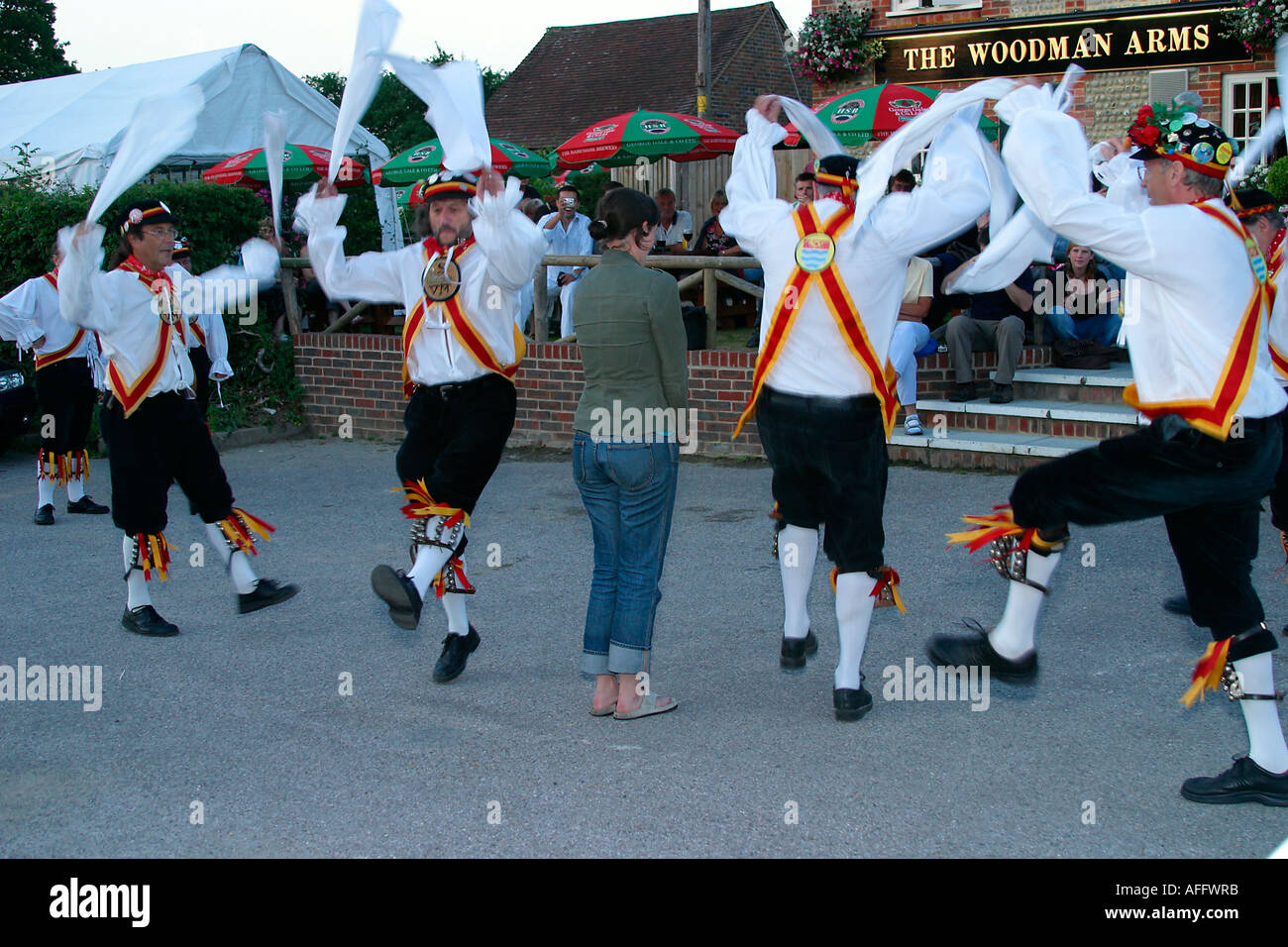 Morris ballerini eseguono balli tradizionali su una serata estati al di fuori di una Sussex public house con un membro del pubblico Foto Stock