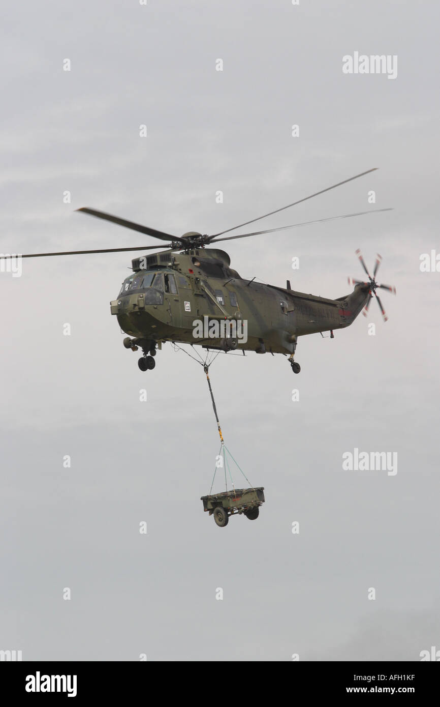 Royal Navy Sea King HC4 Commando truppa d'assalto trasporto in elicottero underslung con veicolo carico del rimorchio Foto Stock