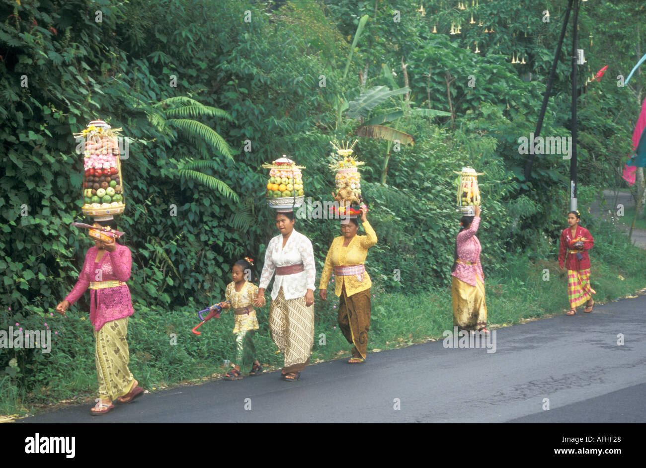 Bali le donne a piedi alla cerimonia il trasporto di frutta sulle loro teste Indonesia Foto Stock