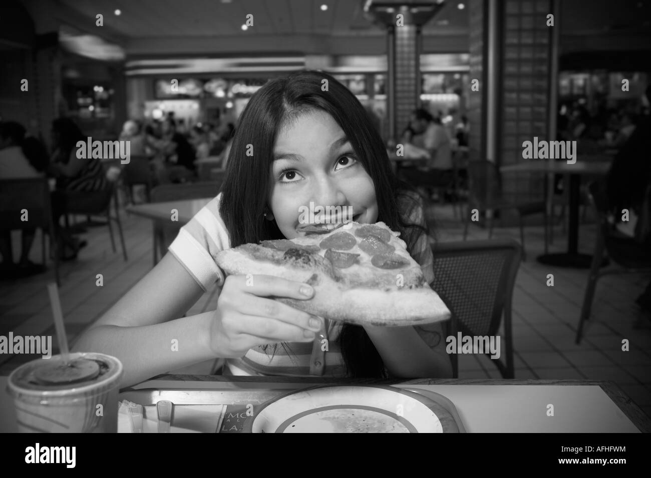 Ragazza adolescente mangiare la pizza nel food court Foto Stock