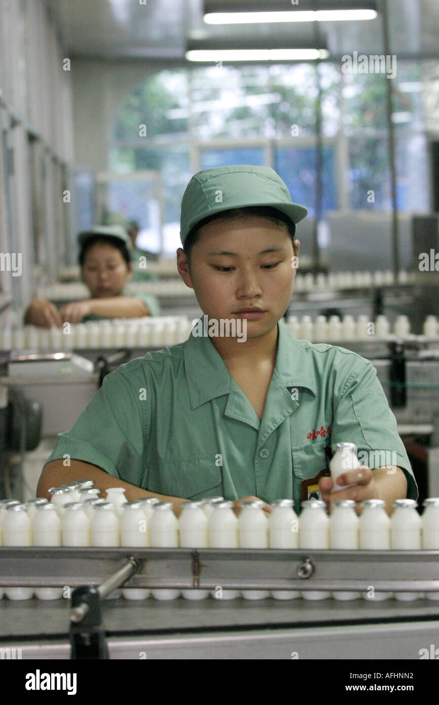 Giovane donna in uniforme verde e cappello che lavora sulla linea di produzione del latte di Wahaha Soft Drinks and Water Corporation. Foto Stock