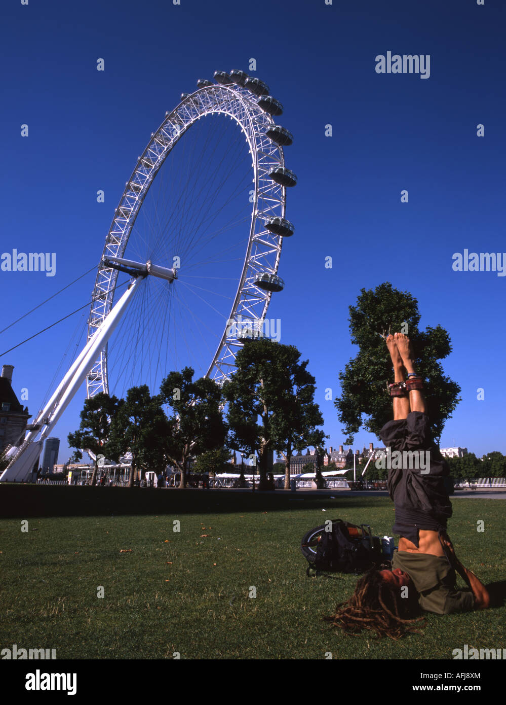 Giovane uomo fa yoga di fronte il London Eye Millennium Wheel, sulla sponda meridionale del fiume Tamigi Foto Stock