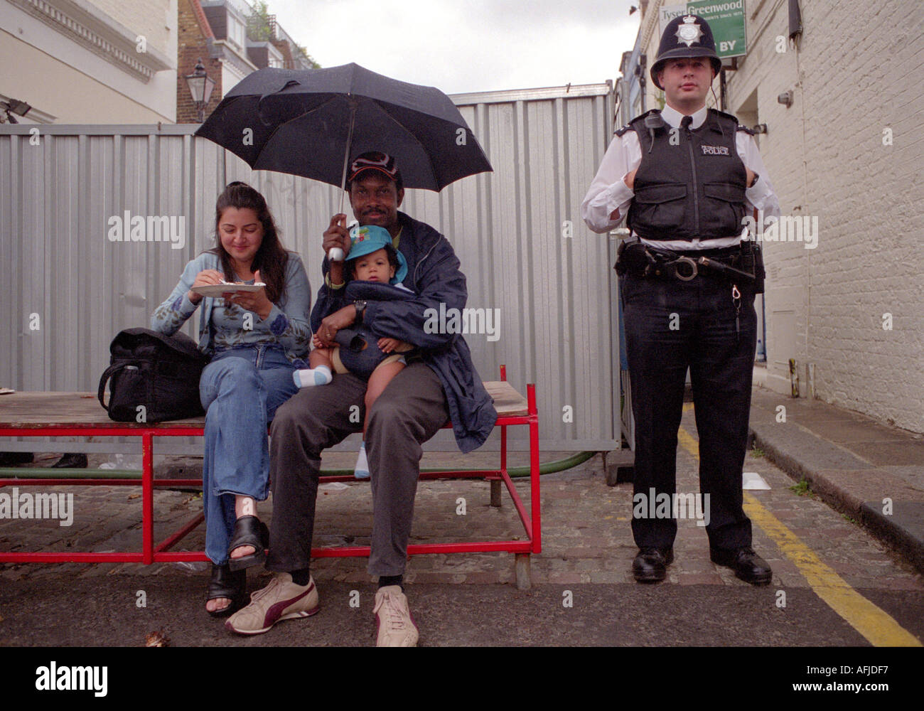 Giovane con il bambino seduto sul banco di lavoro con take away pasto con la polizia sulla battuta in piedi accanto a loro. Foto Stock