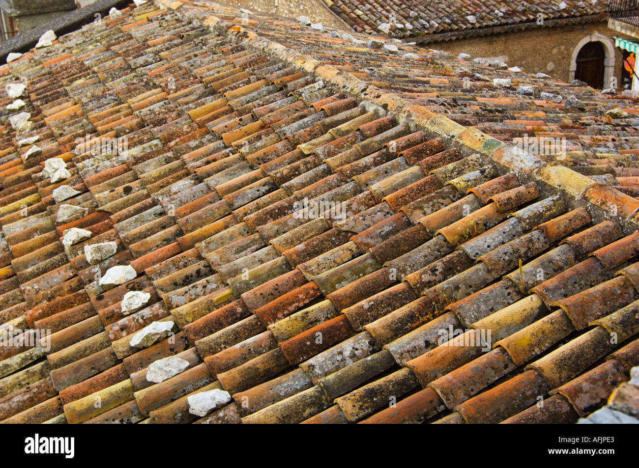 La sovrapposizione di muschi e licheni coperti di terracotta tegole del tetto vicino fino al passo di un tetto a Castelmola Italia sulla Sicilia Foto Stock