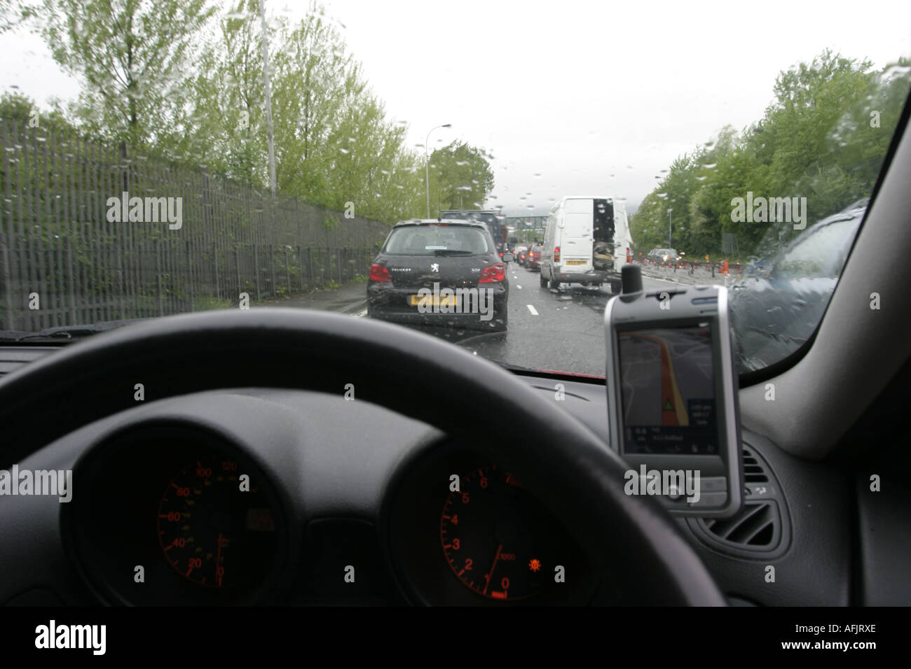 Cruscotto e volante della vettura bloccato nel traffico su Rainy day utilizzando PDA sat nav su dal Westlink Foto Stock