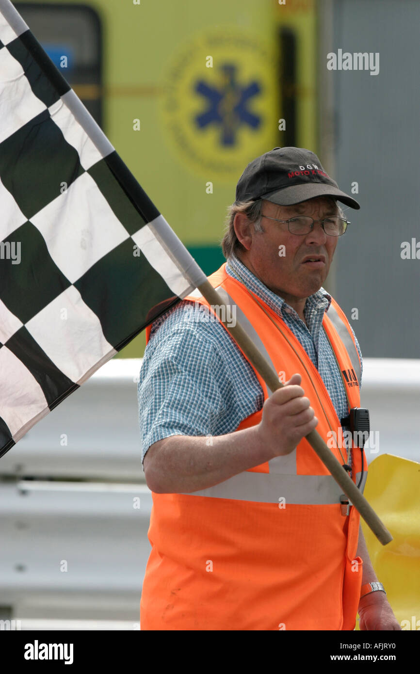 Motorsport marshall in orange hi vis gilet e cappello da baseball porta  bandiera a scacchi davanti a personale paramedico ambulanza Foto stock -  Alamy