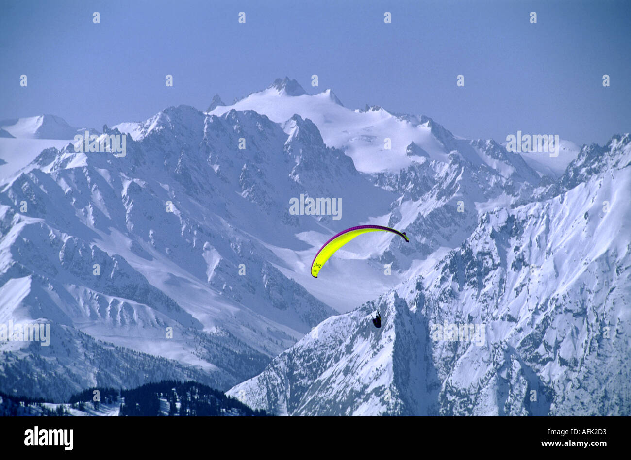 Un solitario pilota di parapendio svetta tra le cime innevate delle tre valli ski area nelle Alpi francesi Foto Stock