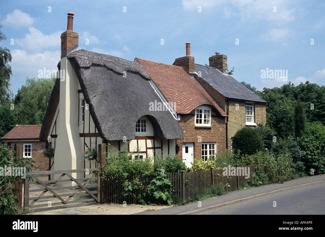 Fila di tre cottage con il tetto di paglia con, piastrellate e tetti di ardesia Foto Stock