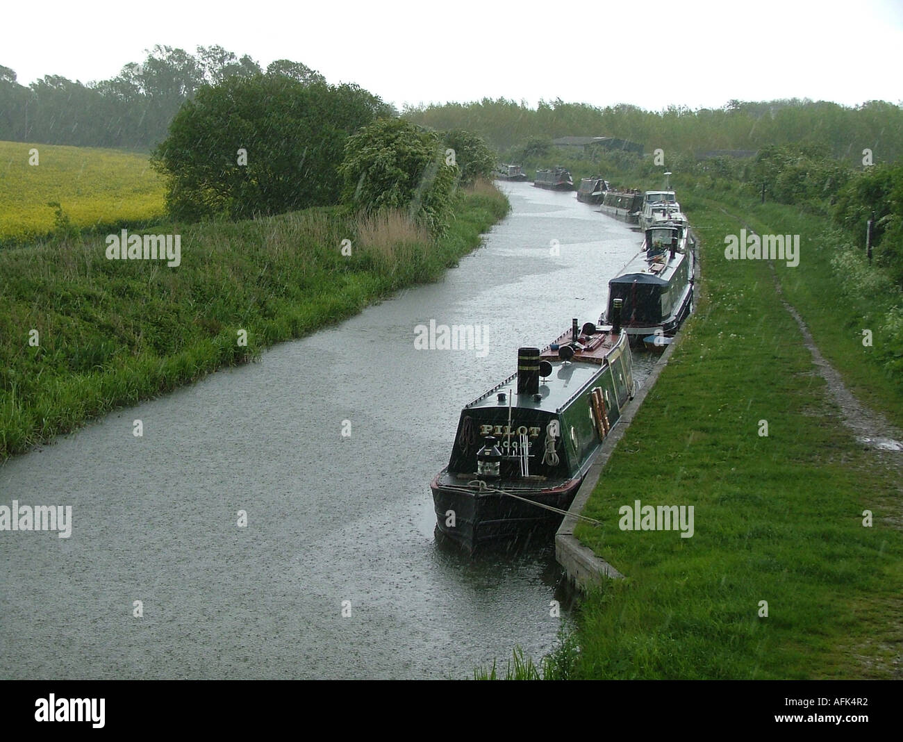 Restringere le barche attraccate al lato del Kennet & Avon Canal, Wiltshire, Inghilterra, durante la pioggia. Foto Stock
