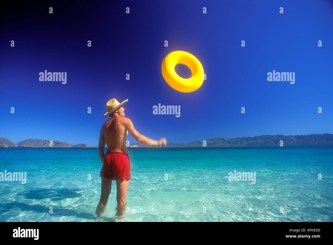 L'uomo gettando giallo anello galleggiante in aria in Baja California Messico Modello rilasciato Image Foto Stock
