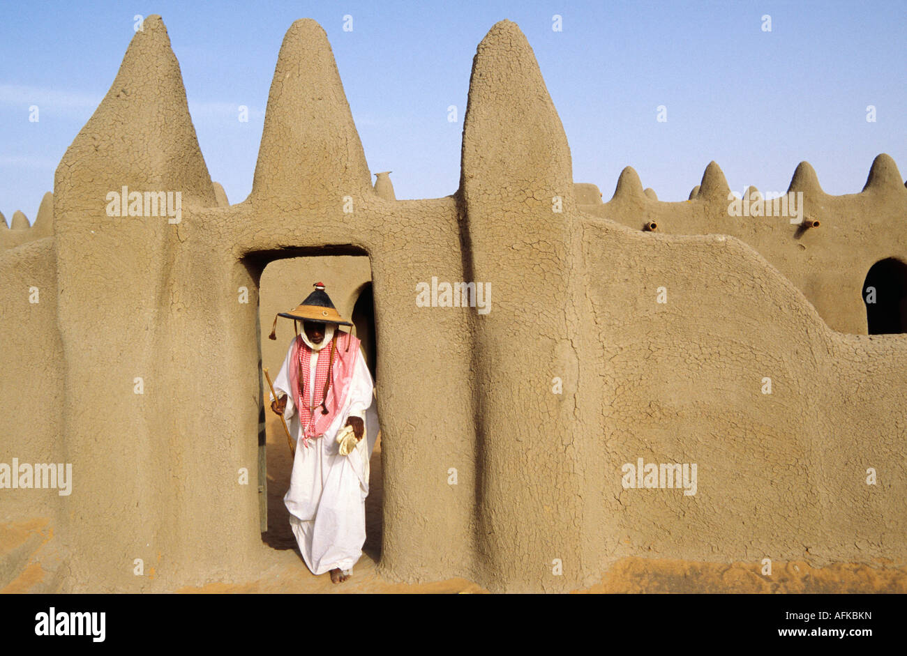 Un pellegrino emerge dalle preghiere in un tradizionale moschea di fango vicino a Djenne in Mali. Foto Stock