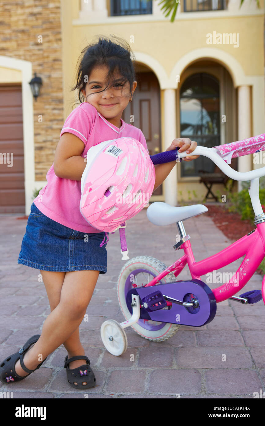 Ritratto di una ragazza in piedi e tenendo una bicicletta nella facciata di una casa Foto Stock