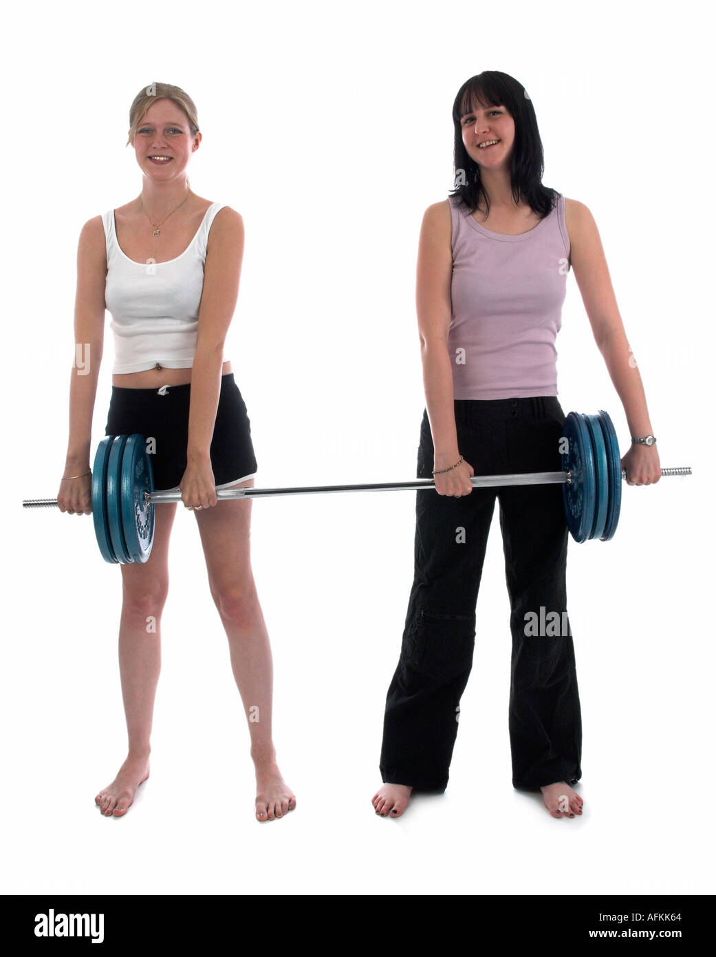 Due giovani donne sorridenti tenendo un pesante barbell e divertirsi Foto Stock