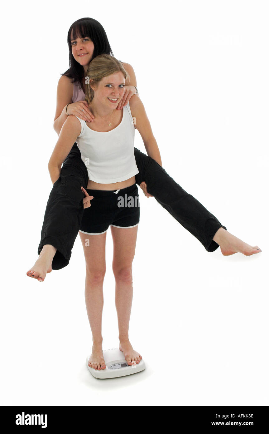 PIGGYBACK Peso Bilancia Peso insieme due giovani donne femmina peso bilancia Foto Stock