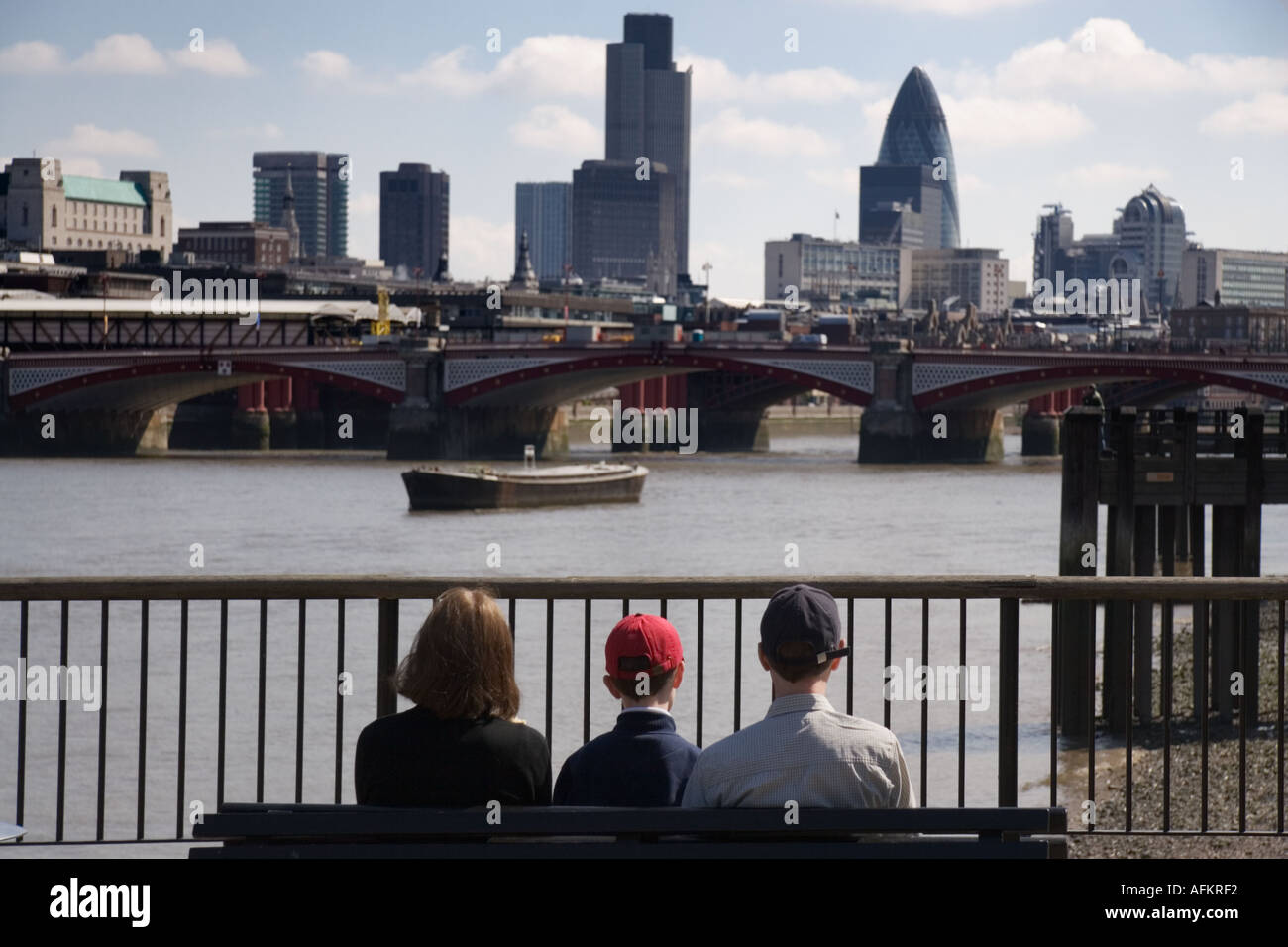 Una madre e padre di un figlio seduto su una panchina dal fiume Tamigi guardando la città di Londra REGNO UNITO Foto Stock
