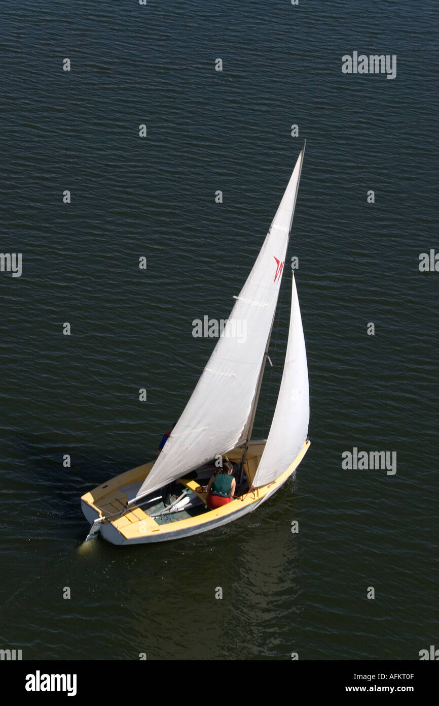 Vista aerea della piccola barca a vela con una donna seduta sul lato di dritta Foto Stock