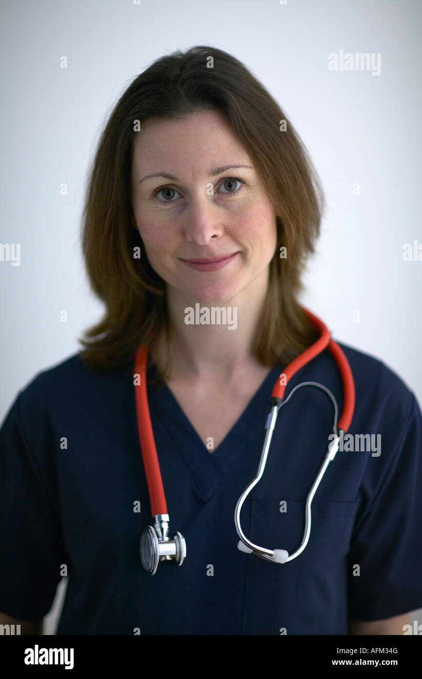 Ritratto di donna medico in blu Scrubs con uno stetoscopio intorno alle spalle guardando la fotocamera Foto Stock