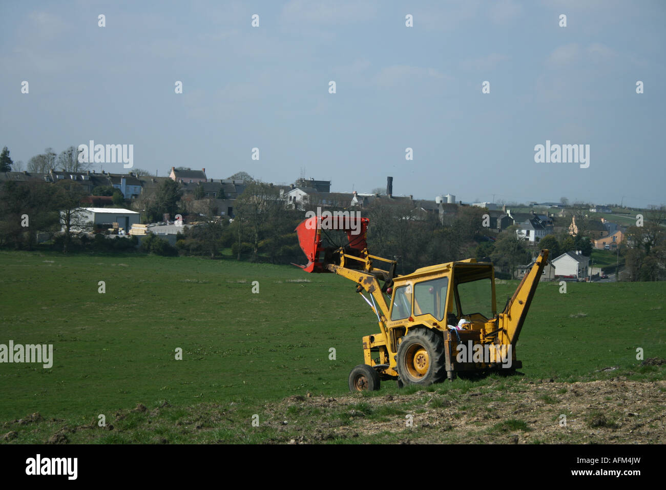 Giallo con il trattore rosso in scavo Killeshandra, Co. Cavan, Irlanda Foto Stock