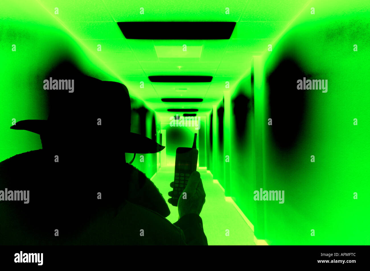Vista concettuale del misterioso uomo scuro con un telefono cellulare è saturo corridoio verde Foto Stock