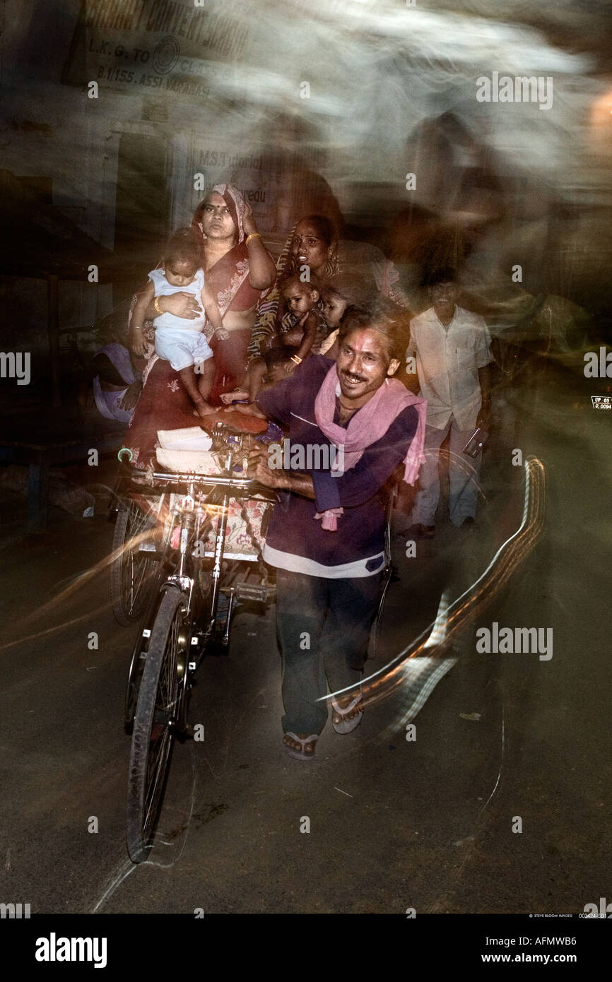 Chi viaggia in famiglia sul risciò bicicletta di notte Varanasi India Foto Stock