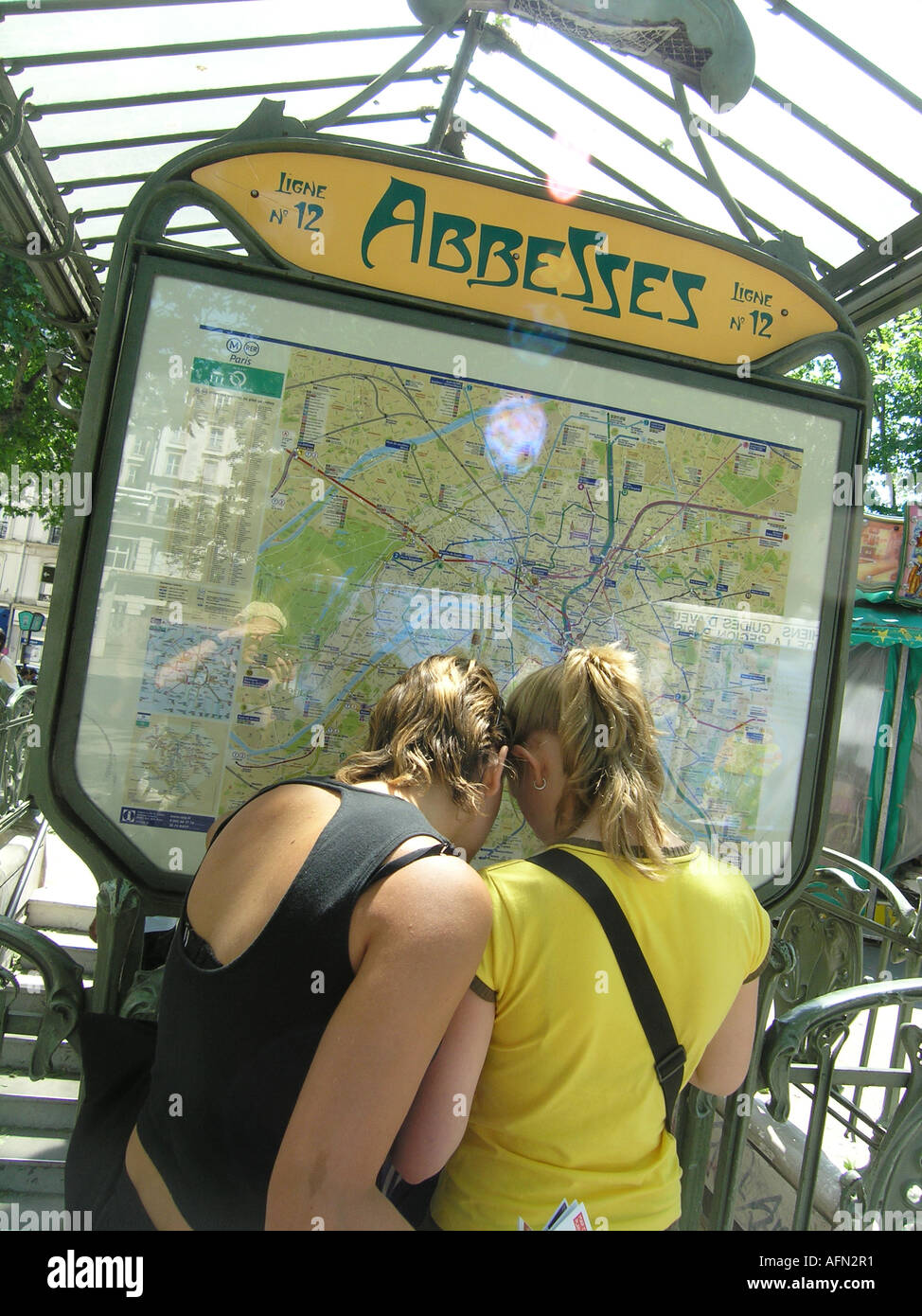 Due ragazze adolescenti guardando la mappa della metropolitana di Parigi sistema in ingresso al Place des Abbesses Montmartre Parigi Francia Foto Stock