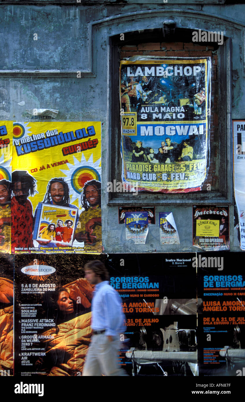 Portogallo Lisbona un uomo a piedi giù per una strada da una parete ricoperta di poster Foto Stock