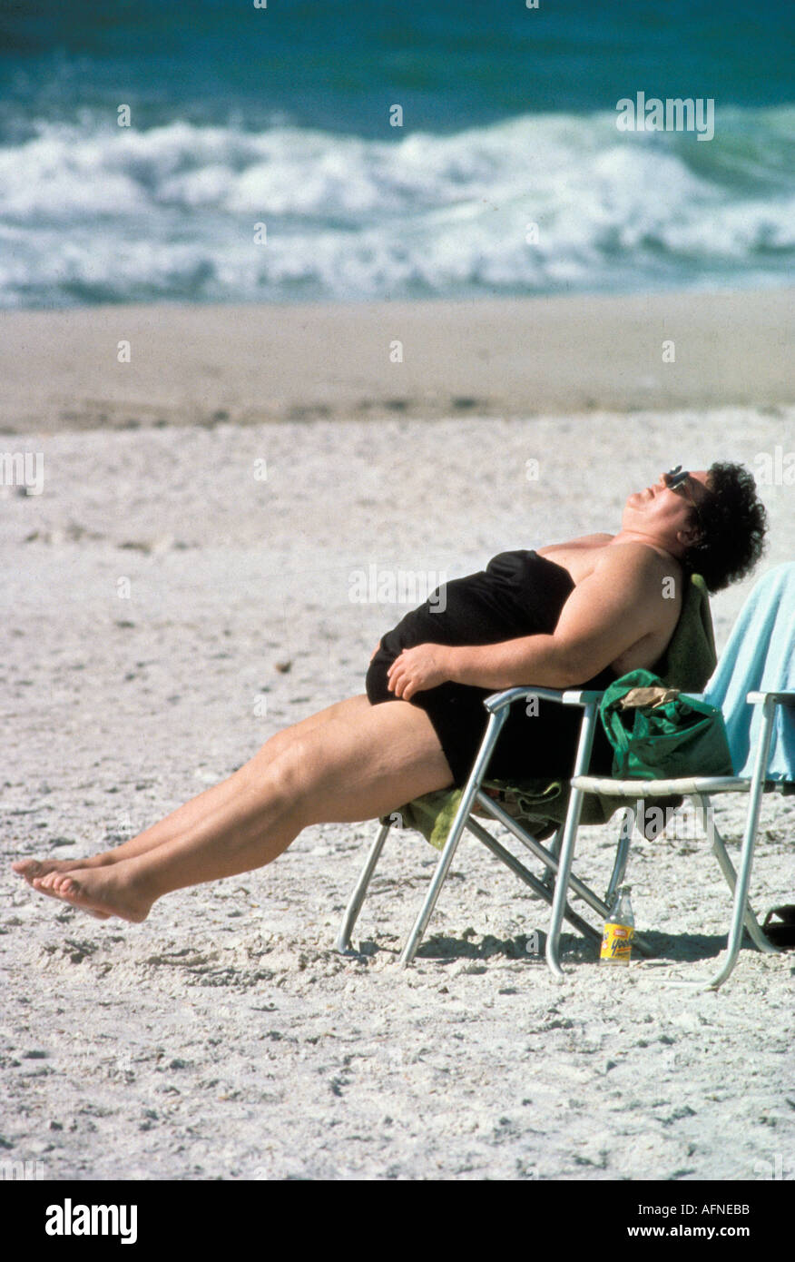 Donna sovrappeso non esercizi di stretching mentre è seduto in una sedia sulla spiaggia Foto Stock