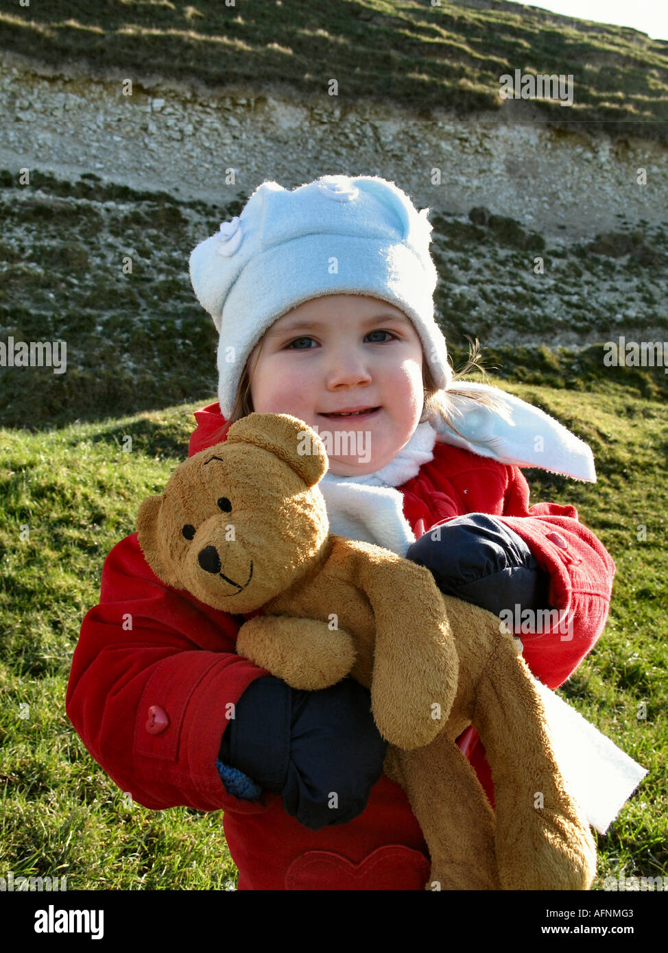 È una ragazza sorridente felicemente con un orsacchiotto di peluche a sette sorelle Country Park in Eastbourne East Sussex Foto Stock