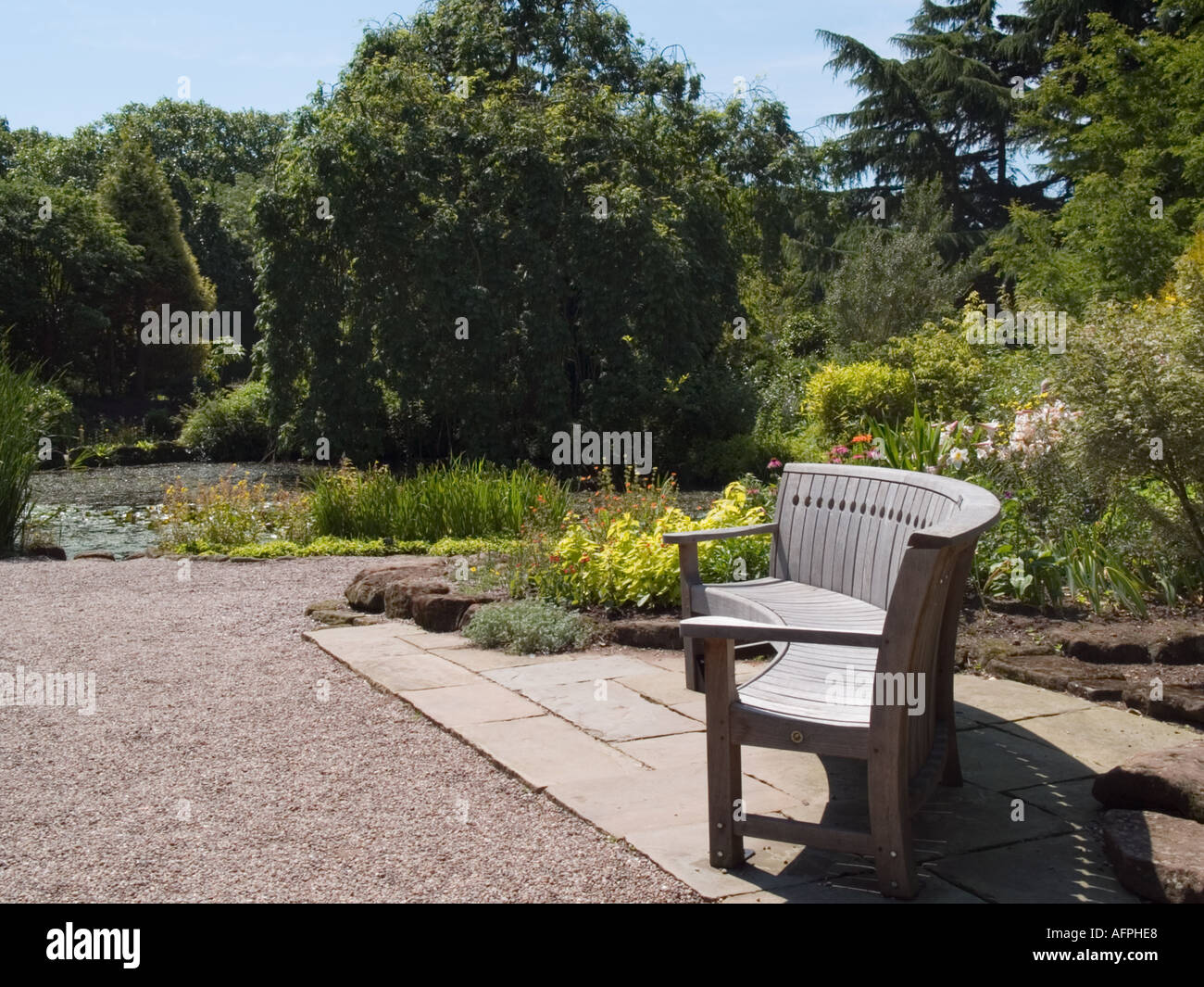Giardini Botanici di Ness in legno curvato sedile e laghetto in giardino di roccia Neston Cheshire England Regno Unito Foto Stock