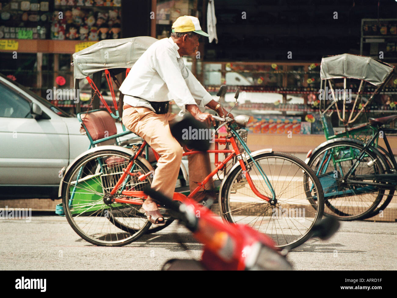 L'uomo pedalando una bicicletta rikshaw taxi in Melaka Malaysia Foto Stock