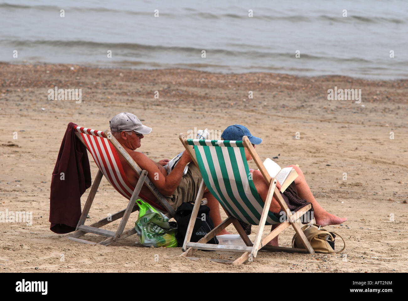 Coppia di anziani la lettura sulla spiaggia di Weymouth in Inghilterra Foto Stock