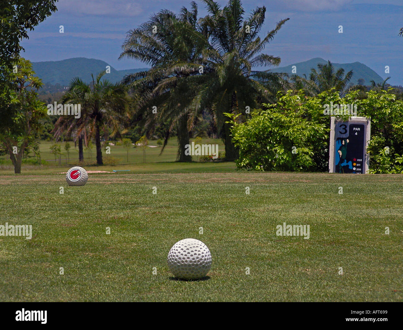 Pheonix Golf e Country Club di Pattaya Thailandia, arbusti e palme a bordo del verde, montagne in distanza. Green numero 3 buche, par 4. Foto Stock