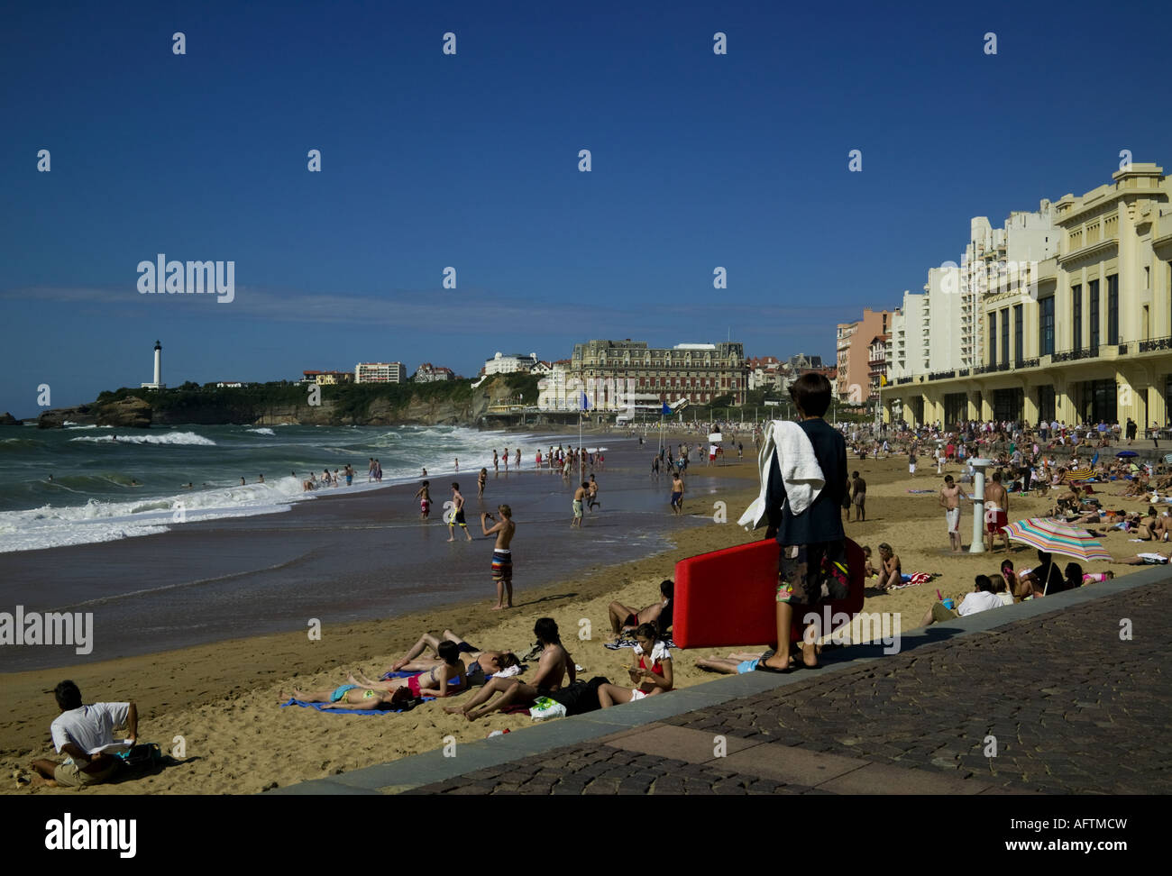 Il lungomare e la passeggiata lungomare di Biarritz, Francia Europa con lucertole da mare e il corpo del surfista in primo piano e il faro Foto Stock