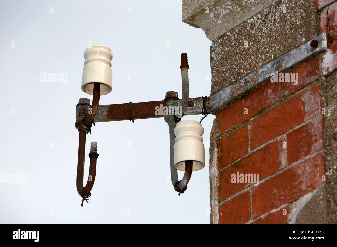Vecchio telefono pothead isolatori di linea leggermente danni due missing attaccato a scorrere verso il basso il vecchio edificio di mattoni rossi Foto Stock