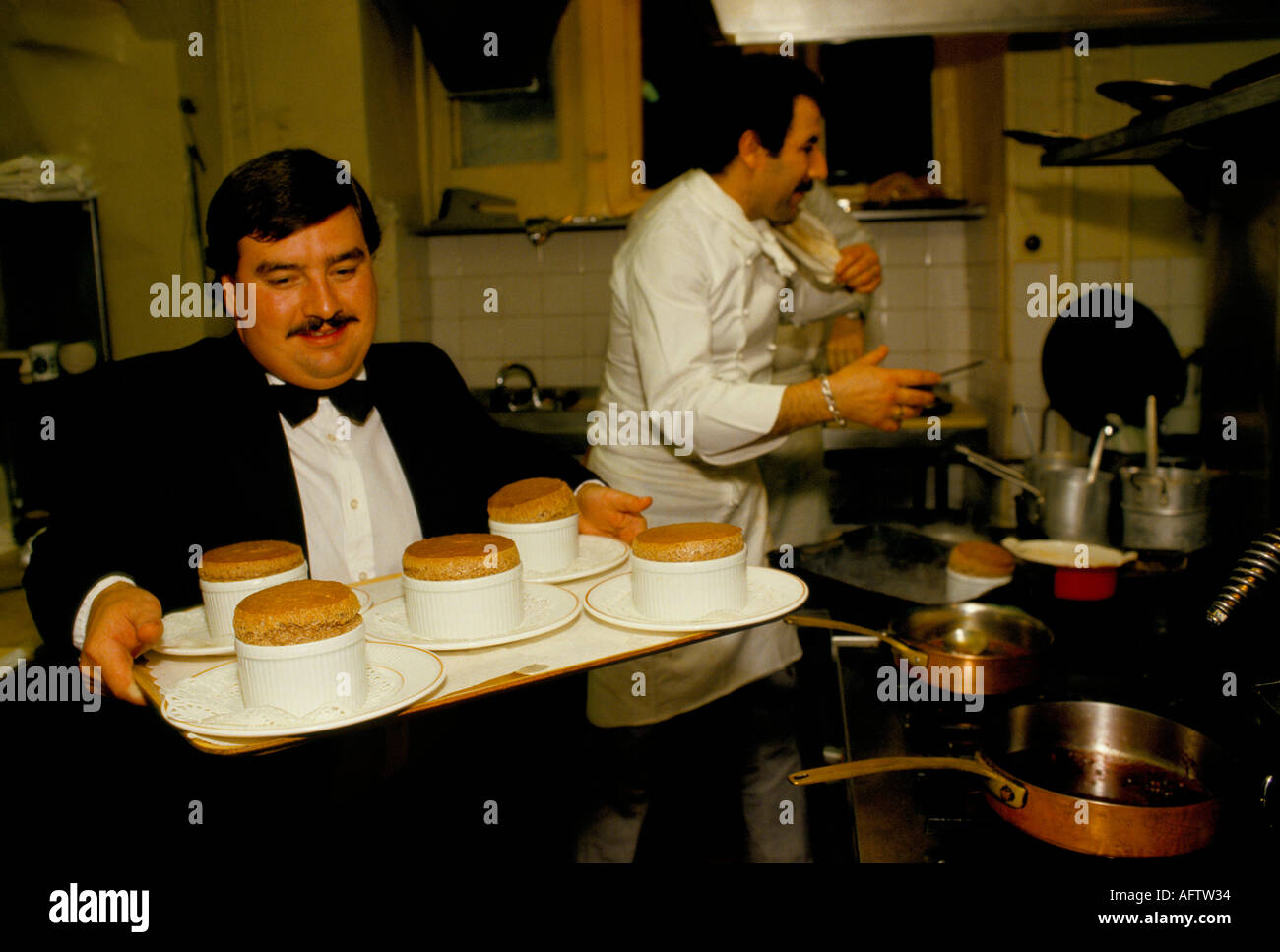 Hotel Work anni '1990 Regno Unito. Lavora come cameriere, cuoco in cucine, lavoro poco retribuito. Con un vassoio di budini in procinto di essere servito agli ospiti. Oxfordshire. Foto Stock