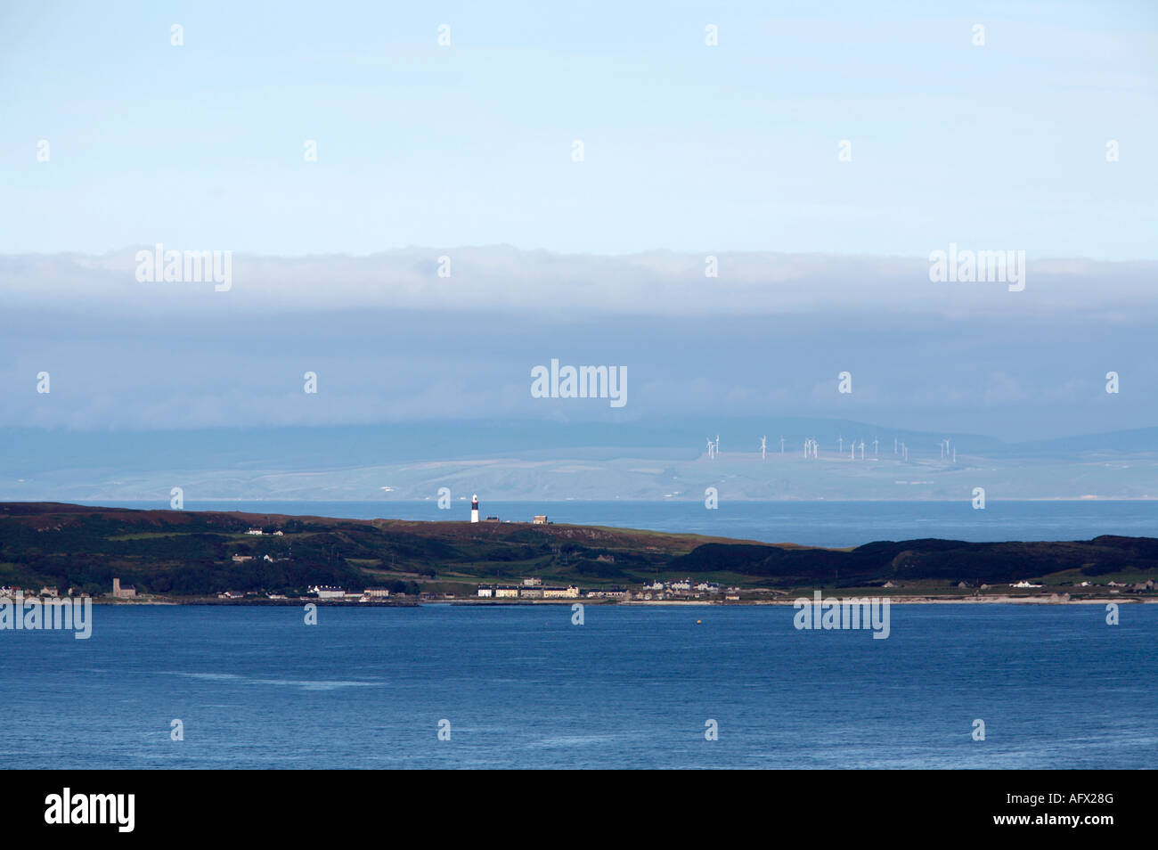 Guardando sulla baia di chiesa e oriente faro di isola di Rathlin verso la terraferma scozzese Mull of Kintyre e wind farm Foto Stock