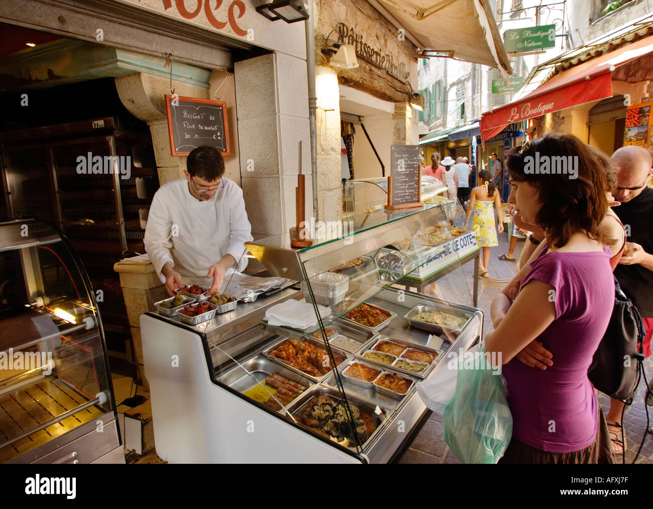 Shop assistant serve clienti in un quartiere vecchio negozio di gastronomia, Vence, Cote d'Azur, in Francia, in Europa Foto Stock