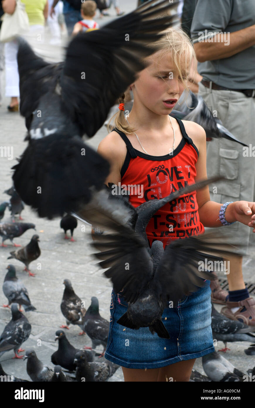 Ragazza giovane alimentare piccioni in Rynek Glowny piazza del mercato, Cracovia,Polonia, Europa orientale Foto Stock