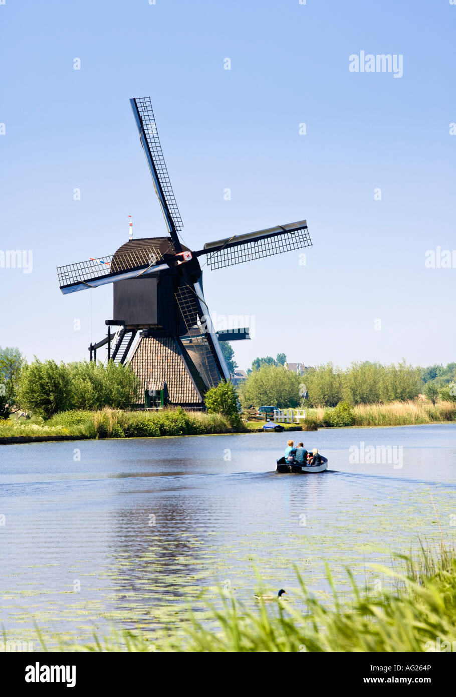 Piccola imbarcazione passa da un mulino a vento a Kinderdijk, Paesi Bassi, Olanda, Europa Foto Stock