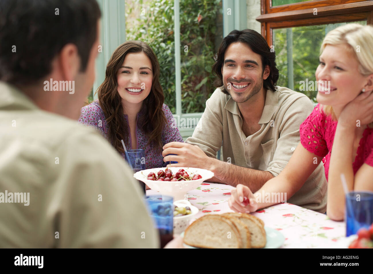 Un gruppo di giovani seduti al tavolo della veranda, ridendo Foto Stock