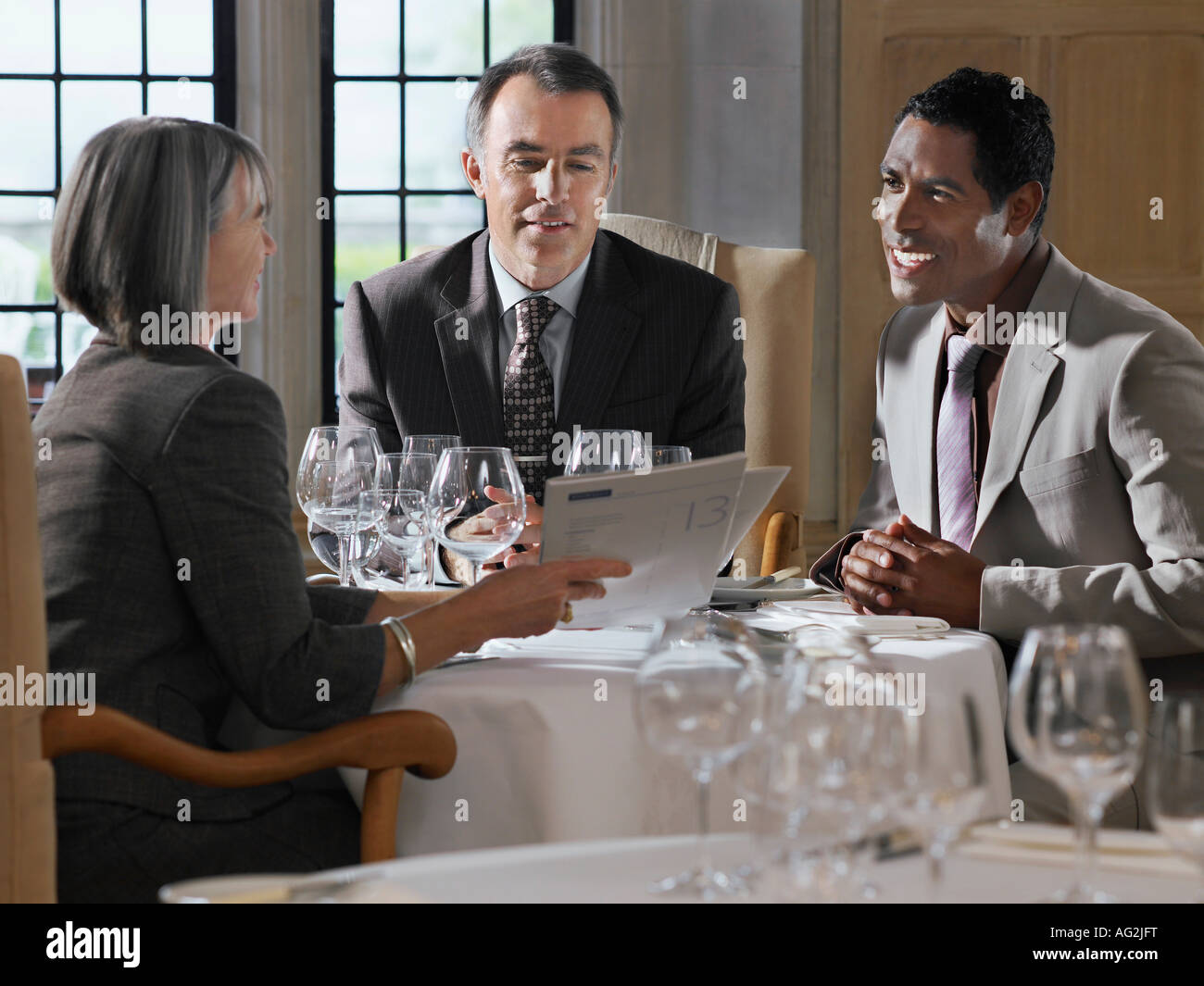 Tre persone sedute al ristorante tavolo, donna che mantiene i documenti Foto Stock