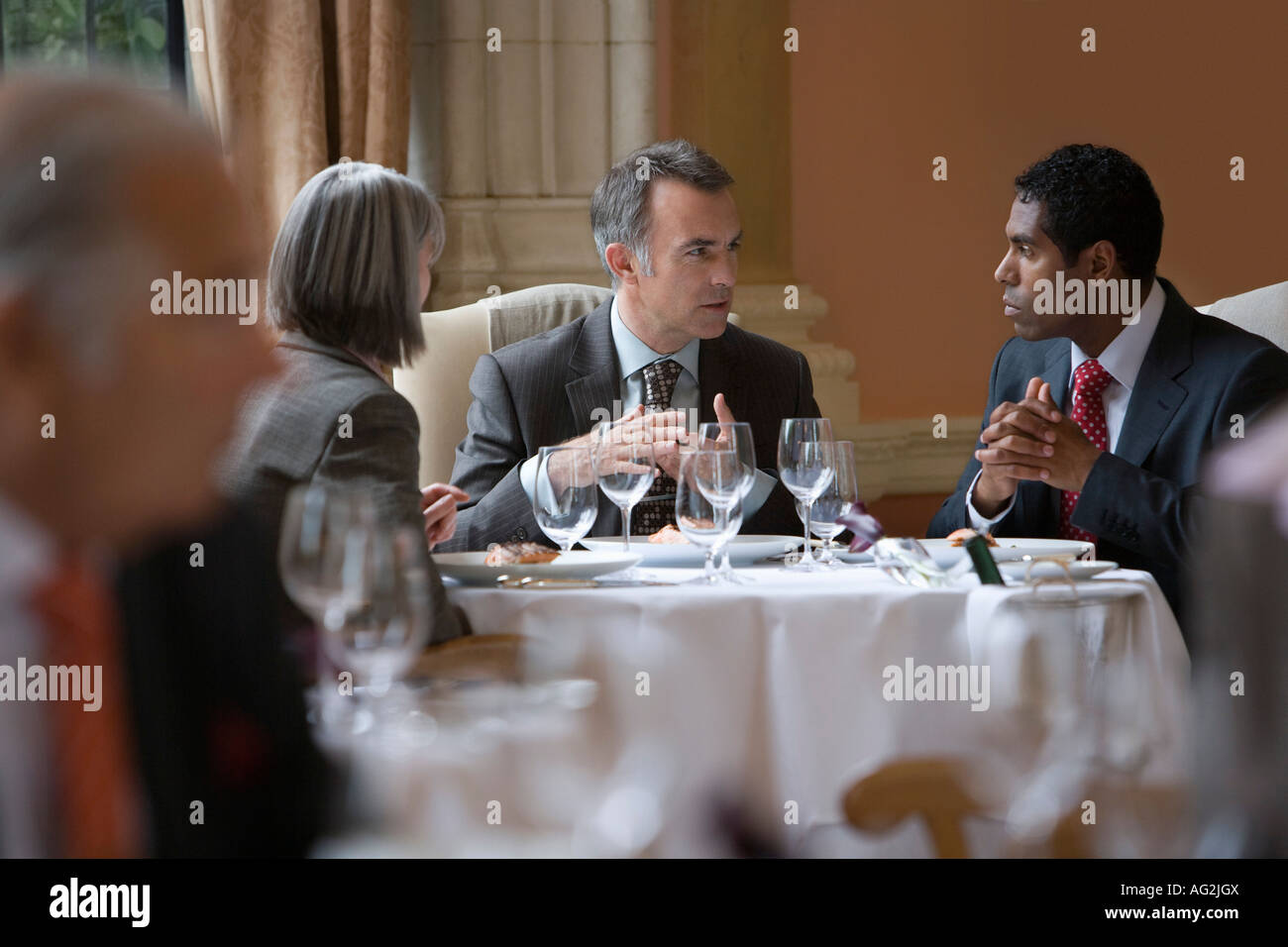 Tre persone sedute al ristorante tavolo, parlando Foto Stock