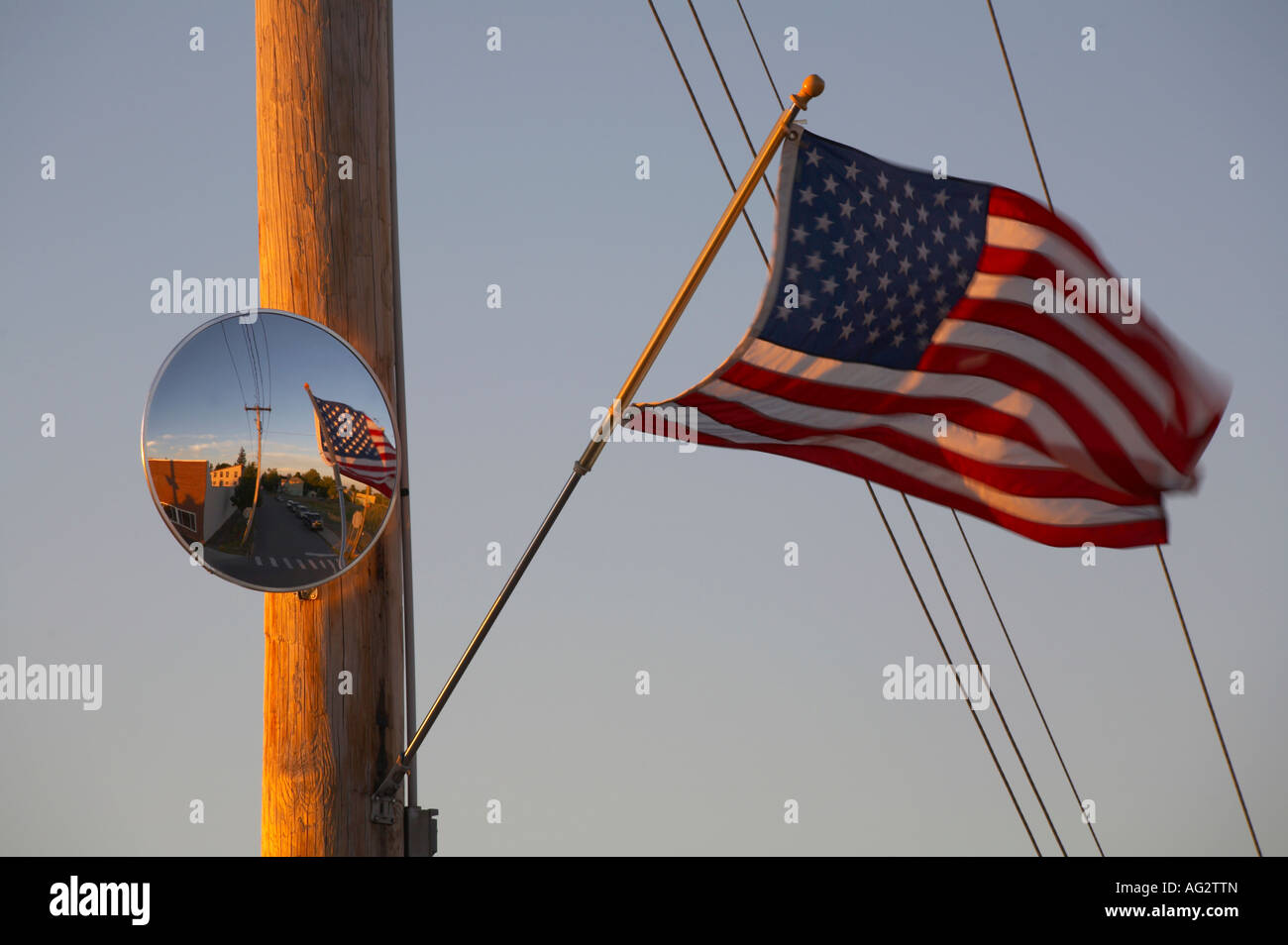 Bandiera americana su un palo telefonico con specchio nella luce del tramonto Foto Stock