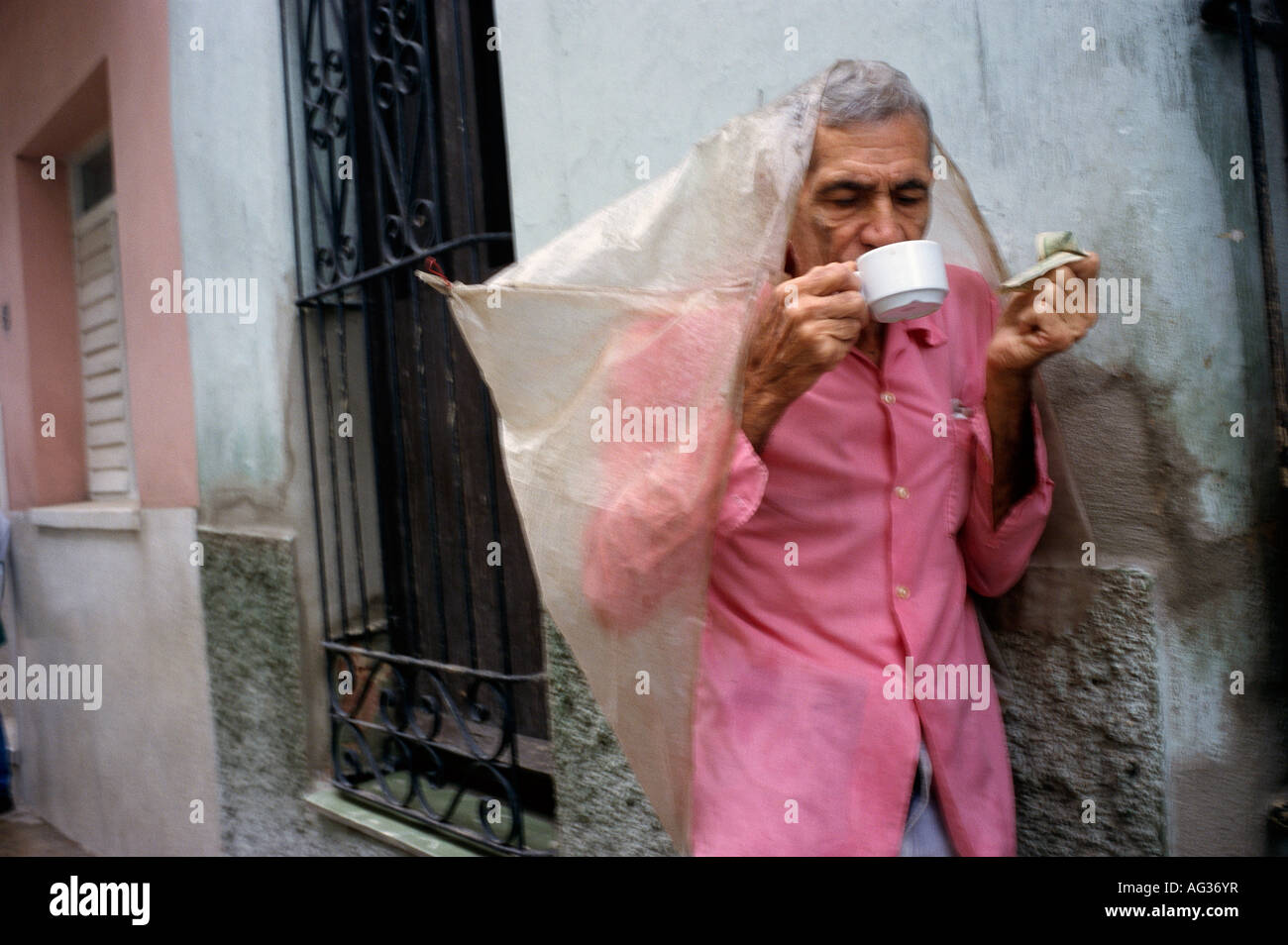 Uomo di bere il caffè in via un giorno drizzly in Santa Clara Cuba Foto Stock